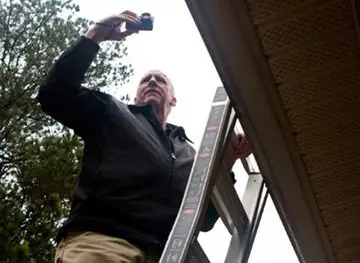 A man standing on a ladder holding a camera.