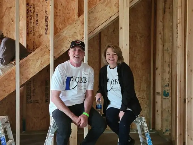 A man and woman sitting on ladders in a construction site.
