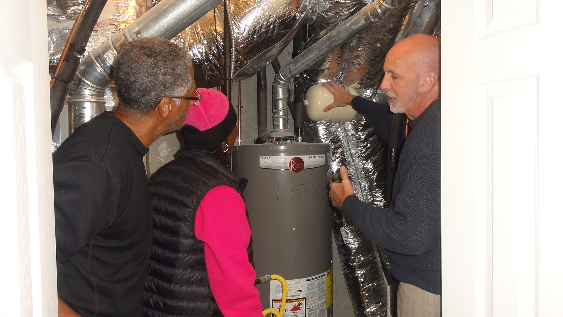 A group of people looking at a water heater.