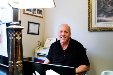 A man sitting at a desk with a laptop in front of him.